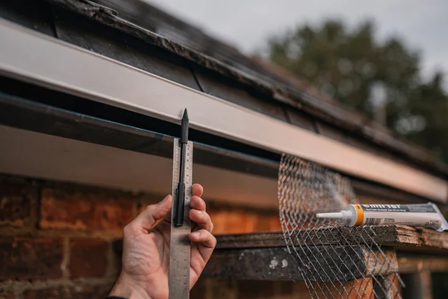 Macro close-up of a continuous soffit ventilation gap under a London roof edge, showing a narrow entry point that explains why cluster fly infestation prevention in autumn often fails