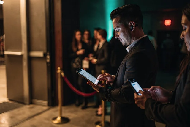 VIP host scanning a guest's phone at the velvet rope with a tablet during nightclub door check-in, one of the practical tests for choosing bottle service table reservation software.
